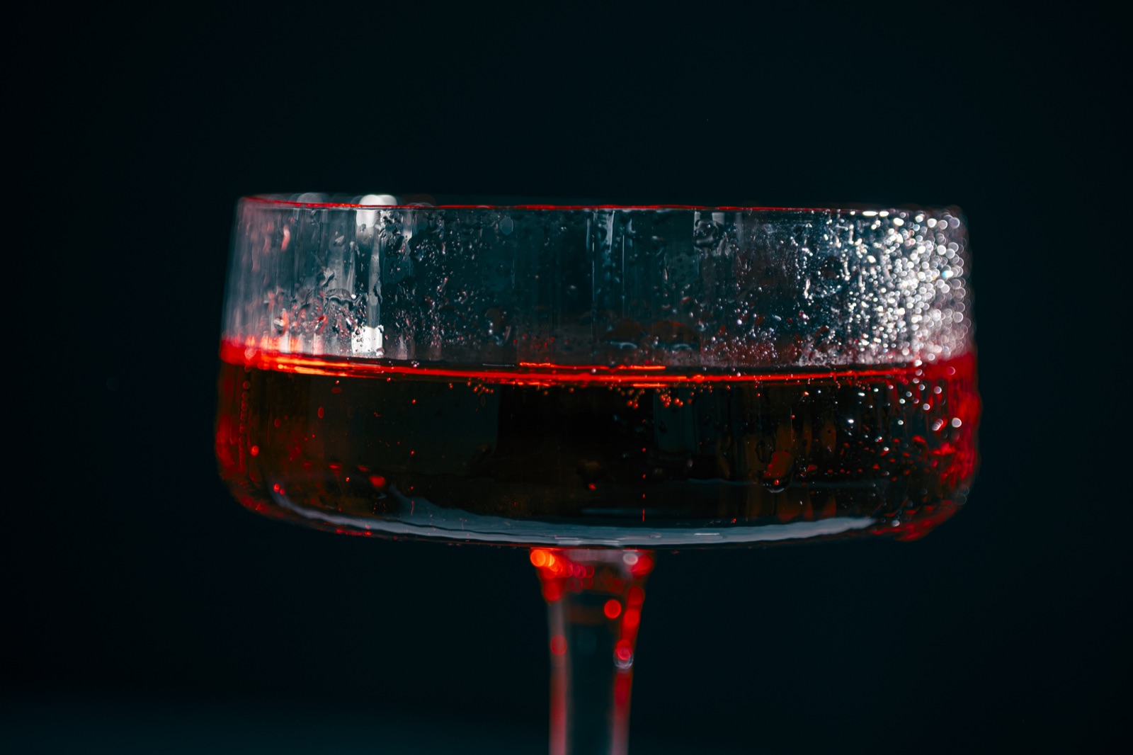 Close-up of a red drink in a coupe glass with condensation